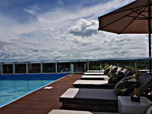 um deque com espreguiçadeiras e um guarda-sol junto a uma piscina em O2 Hotel Iguazu em Puerto Iguazú