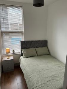 a bedroom with a bed and a lamp and two windows at Flat 3 Rylands Street in Warrington