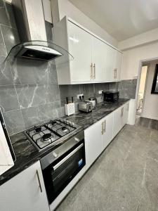 La cuisine est équipée de placards blancs et d'un four avec plaques de cuisson. dans l'établissement Shoreditch Rooms R2, à Londres