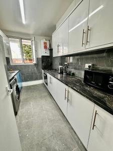 une cuisine avec des placards blancs et un comptoir noir dans l'établissement Shoreditch Rooms R2, à Londres