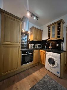 a kitchen with wooden cabinets and a washing machine at Flat 3 Rylands Street in Warrington