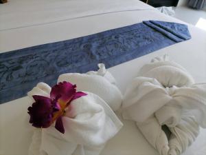 two towels on a bed with flowers on it at NJ PATONG HOTEL in Patong Beach