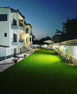 a large yard with green grass in front of a building at Sun Day Apartments Free Airport Shuttle in Artemida