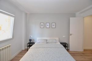 a white bedroom with a bed and two tables at STAY Las Segadas in Oviedo