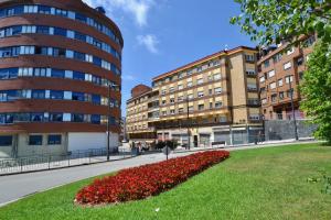 eine Stadtstraße mit Gebäuden und einem Feld voller roter Blumen in der Unterkunft STAY Las Segadas in Oviedo