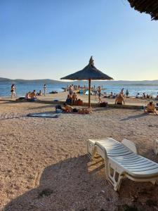um grupo de pessoas em uma praia com um guarda-sol em lastva 1&2 em Sveti Filip i Jakov