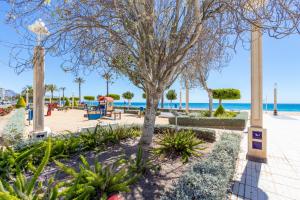 a park with a tree and the beach in the background at Altea Playa Roda in Altea