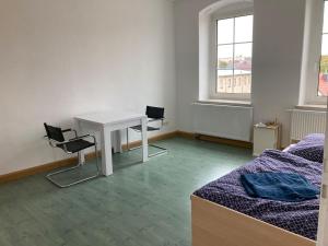 a room with a desk and two chairs and a bed at Monteurswohnung Place2stay in Großenhain in Großenhain