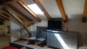 Casa vacanze - alloggio agrituristico Col في Monrupino: غرفة معيشة مع تلفزيون وخزانة مع كراسي