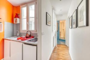 a kitchen with orange walls and white cabinets and a sink at Stunning Apartment 2br + balcony + nice view in Paris