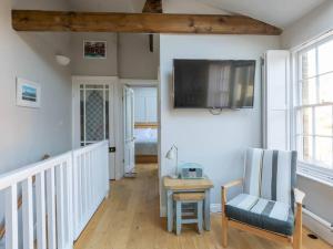 een woonkamer met een tv, een stoel en een tafel bij The Coach House - Unique split level property in Kent