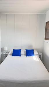 1 dormitorio con 1 cama blanca grande con almohadas azules en Villa Mi Olvido V.V., en Sardina