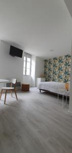 een grote witte kamer met een bed en een stoel bij Agréable studio in Bourgueil