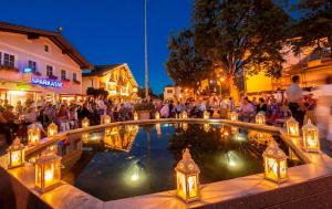 um grupo de pessoas sentadas em torno de uma piscina à noite em Ferienhaus Altenmarkt, Kaulfersch em Altenmarkt im Pongau