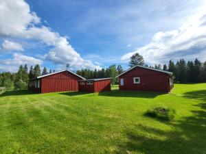 two red buildings on a green field with trees at Stugby Marieke - Skärvången in Föllinge