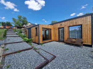 a wooden house with a bench on a gravel yard at Bella Vista Bungalow in Turda
