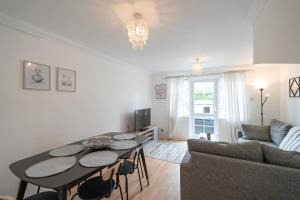 a living room with a table and a couch at Bright and modern 4-bed townhouse with garden near town centre in Kent
