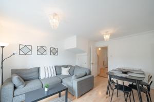 ein Wohnzimmer mit einem Sofa und einem Tisch in der Unterkunft Bright and modern 4-bed townhouse with garden near town centre in Kent