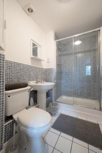 ein Bad mit einem WC, einem Waschbecken und einer Dusche in der Unterkunft Bright and modern 4-bed townhouse with garden near town centre in Kent