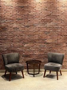 duas cadeiras e uma mesa em frente a uma parede de tijolos em EPIGRAPH Design Hotel em Tbilisi