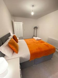 ein Schlafzimmer mit einem großen Bett mit einer orangefarbenen Decke in der Unterkunft Luxurious and Spacious 2 Bedroom Flat in Milton Keynes