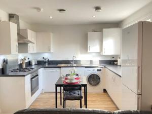 a kitchen with white cabinets and a table with dishes on it at Luxurious and Spacious 2 Bedroom Flat in Milton Keynes