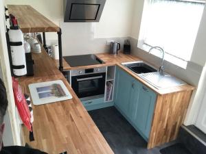 a small kitchen with blue cabinets and a sink at Skippings in Beccles