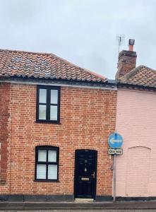 a brick building with a black door on a street at Skippings in Beccles
