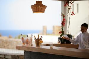 a man pouring a glass of wine at a bar at Summer Senses Luxury Resort in Logaras