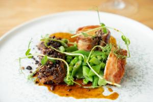 a plate of food with meat and greens on it at Fistral Beach Hotel and Spa - Adults Only in Newquay