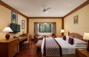 ウーティにあるFortune Resort Sullivan Court, Ooty - Member ITC's Hotel Groupのベッド、デスク、テレビが備わるホテルルームです。