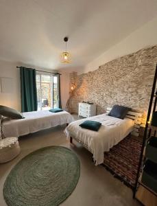 1 Schlafzimmer mit 2 Betten und einer Steinmauer in der Unterkunft Charmant logement in Rogliano