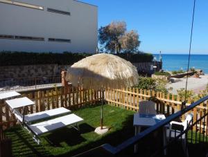 a patio with a straw umbrella and chairs and the ocean at Ville Paola e Daniela in San Vincenzo