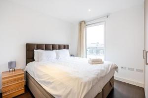 a bedroom with a large bed with a window at Superb 2 bed 2 baths Apartment in Woolwich
