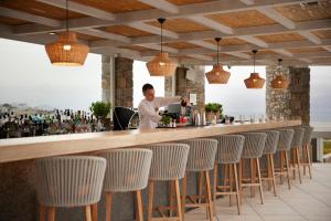 a man preparing a drink at a bar with chairs at Summer Senses Luxury Resort in Logaras