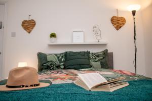 einen Hut und ein offenes Buch auf einem Bett in der Unterkunft Warm and relaxing hideaway in Aintree