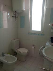 La salle de bains blanche est pourvue de toilettes et d'un lavabo. dans l'établissement Vicino l'Etna, à Tremestieri Etneo