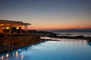 a large swimming pool with a sunset in the background at Summer Senses Luxury Resort in Logaras