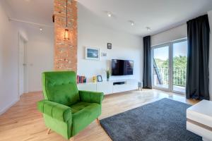 a living room with a green chair and a television at Surf&Sail Apartament Gdynia Orłowo, 400m Plaża, free parking in Gdynia