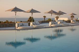 a pool with white lounge chairs and umbrellas at Summer Senses Luxury Resort in Logaras