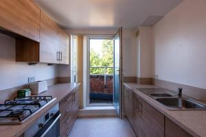 a kitchen with a stove and a sink and a window at 3rd Floor Apt Near QMC Hospital with City Views in Nottingham