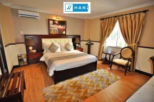 a bedroom with a bed and a chair and a window at HANZ Hoa Huong Duong Hotel in Ho Chi Minh City