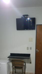 a television on the wall of a room with a chair at Hotel Graunas in São Carlos