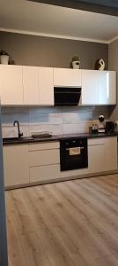 kuchnia z białymi szafkami i drewnianą podłogą w obiekcie Apartament Italia Faktura VAT w Koszalinie