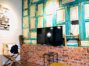 uma sala de estar com uma parede de tijolos e uma televisão de ecrã plano em INS White House Ipoh em Ipoh