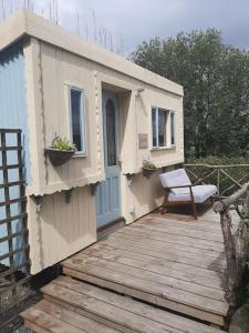 a small shack with a bench on a wooden deck at Off grid Rosie Sheperd hut and summerhouse plus 1 acre at Tanyrallt in Llanybydder