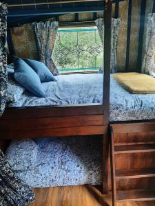 ein Schlafzimmer mit einem Etagenbett und einem Fenster in der Unterkunft Off grid Rosie Sheperd hut and summerhouse plus 1 acre at Tanyrallt in Llanybyther