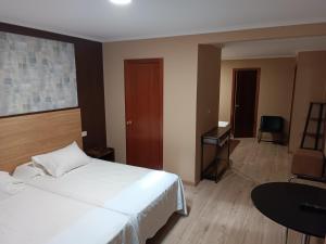 a bedroom with a large white bed and a desk at Cruceiro do Monte in Tui