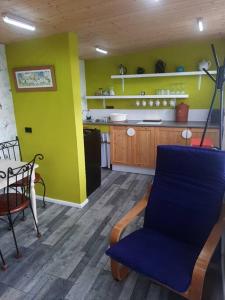 uma cozinha com uma cadeira azul e uma parede amarela em Off grid Rosie Sheperd hut and summerhouse plus 1 acre at Tanyrallt em Llanybyther