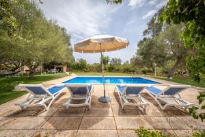 einen Pool mit 2 Stühlen und einem Sonnenschirm in der Unterkunft Villa sa teulada in Santa Margalida